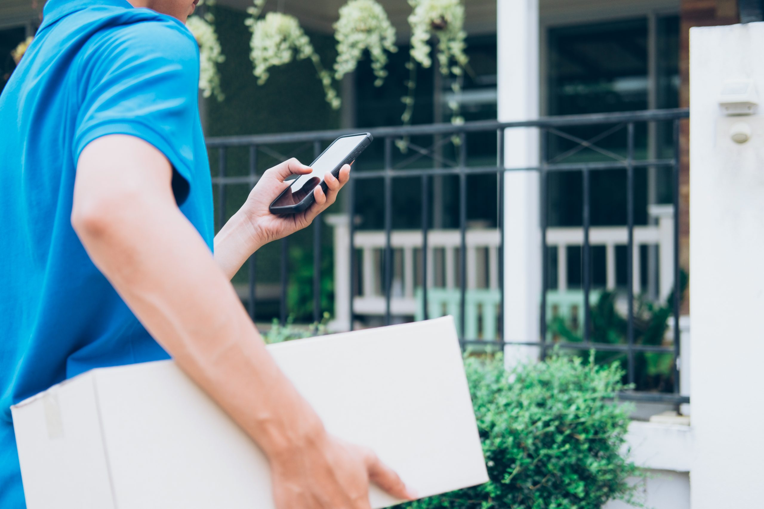 Delivery service courier standing in front of the house with box