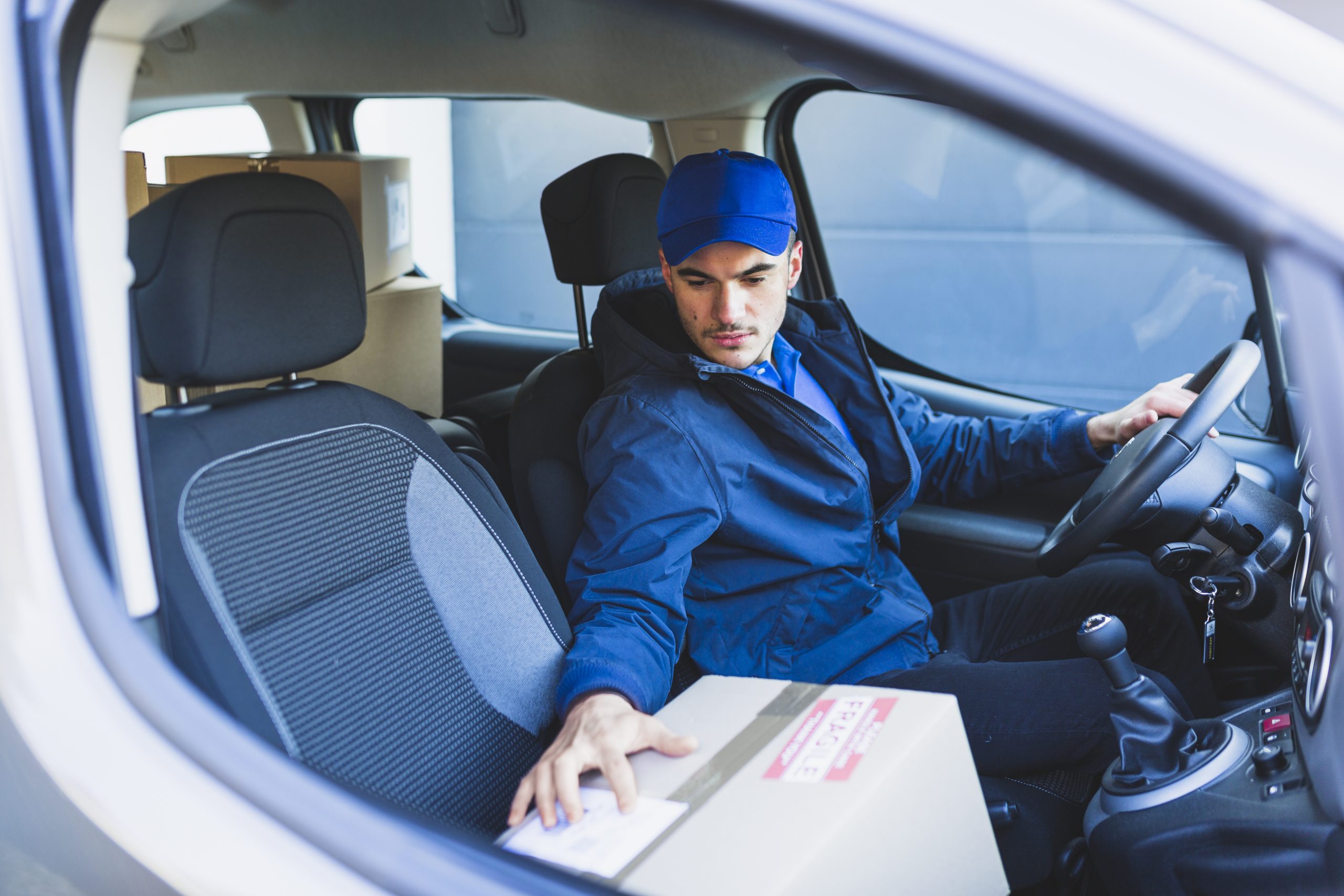 young-courier-delivering-parcel-with-car